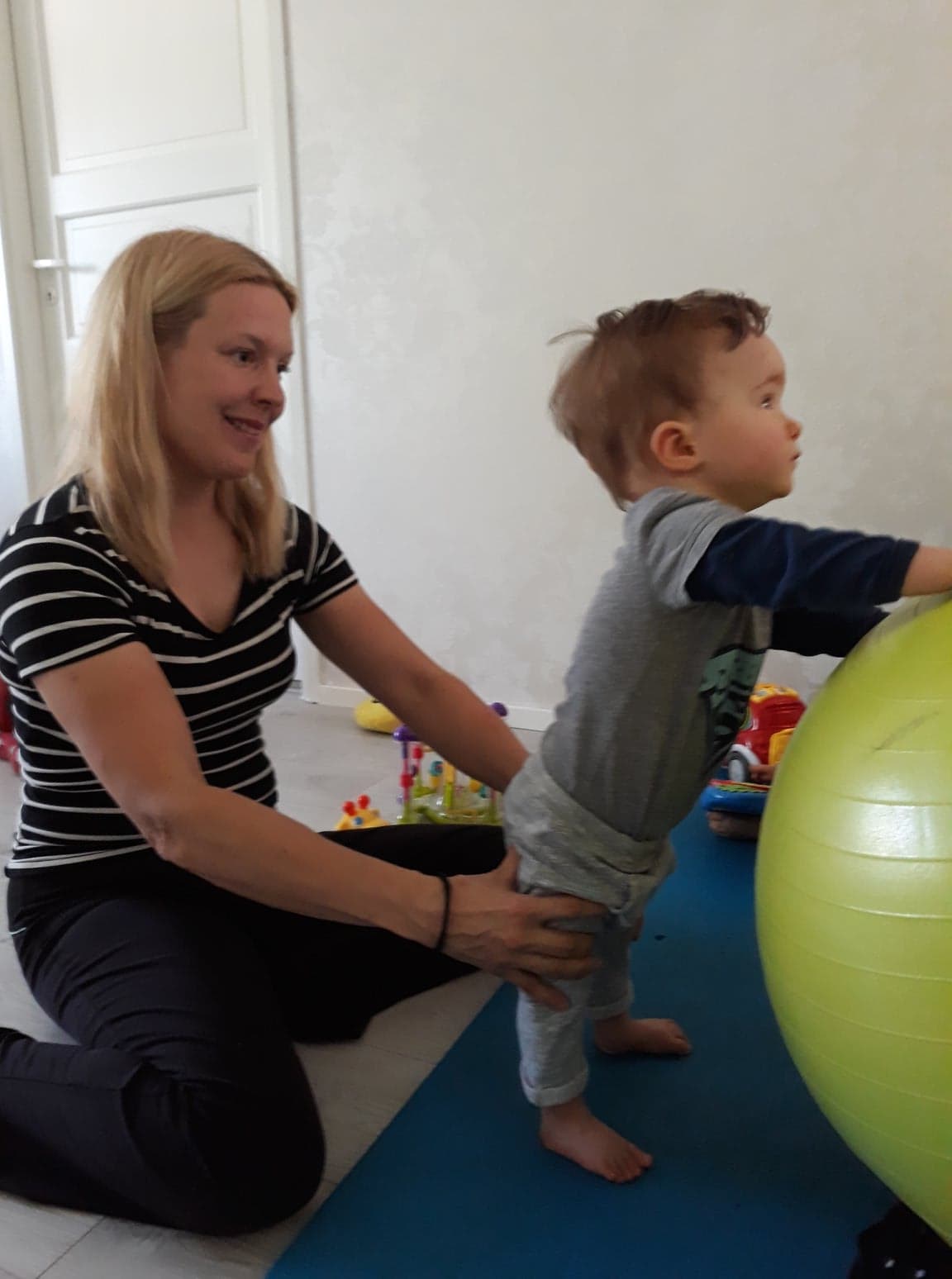 Virpi jumppaa vauva ikäistä lasta jumppapallon kanssa.